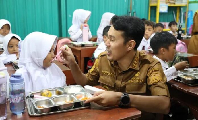Wakil Walikota Serang sedang menyuapi makanan kepada anak SD
